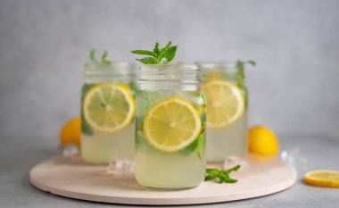 Üç limonlu mojito kokteyli, üzerinde nane şekeri ve ahşap kavanozlar..