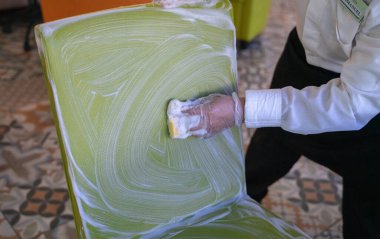 Bir restoranın çalışanı, bir sandalyenin minderlerini yıkıyor.