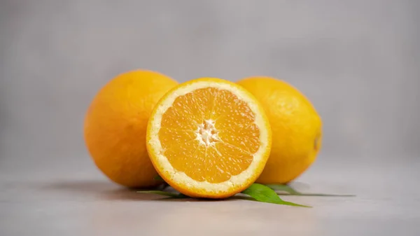 Zwei Orangenfrüchte Mit Einer Geschnittenen Orange Auf Grauem Hintergrund — Stockfoto