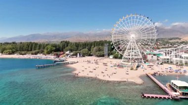 Cholpon-Ata, Kırgızistan 4 Ekim 2025: Issyk-Kul Gölü 'nün yanındaki dönme dolap manzaralı dağlar, popüler bir turistik bölge..