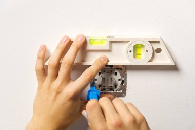 Tadilattan sonra elektrik düğmesi takan adam. Elektrikçi boyalı duvara tornavidayla ışık anahtarı yerleştiriyor.