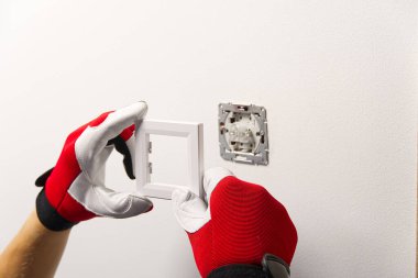 Tadilattan sonra elektrik düğmesi takan adam. Elektrikçi boyalı duvara tornavidayla ışık anahtarı yerleştiriyor.