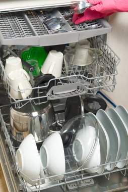 Açık entegre bulaşık makinesinde kirli tabak. Ev hanımının eli bulaşık makinesine kirli bulaşıkları koyuyor. Yıkanmadan önce kirli bulaşıklarla birlikte bulaşık makinesini aç. Kadınlar eldiven takar, tabakları makineye yerleştirir.