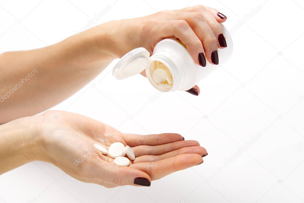white pills in white plastic jar. COVID-19. Medical mask on a hand with white background. Medicine pills against the virus. Hand holds medical jar with pills and white pills on hand.
