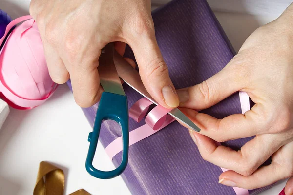 Woman wrapping christmas presents to violet packing paper. woman hands packing a christmas gift, diy gift packing concept — Stock Photo, Image