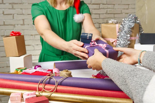 Mani femminili che tengono una piccola scatola regalo avvolta in carta da imballaggio. Per dare e ricevere regali dai propri cari per Natale, San Valentino, compleanno. — Foto Stock