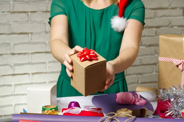 Female hands holding a small gift box wrapped in packing paper. To give and receive gifts from loved ones for christmas, valentines, birthday.