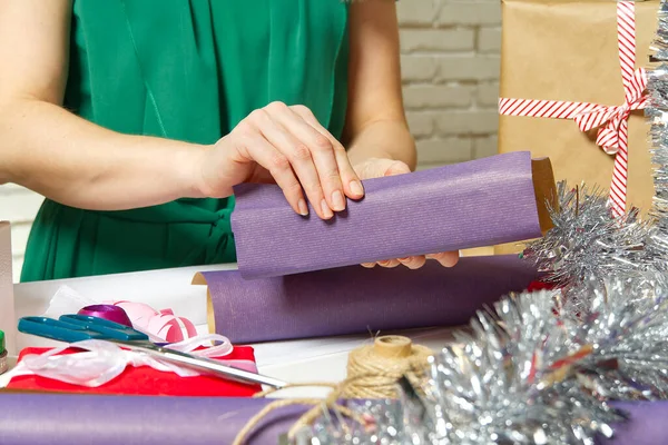 女人包装圣诞礼物给紫罗兰色包装纸.女人的手包装圣诞礼物，阴郁的礼物包装概念 — 图库照片