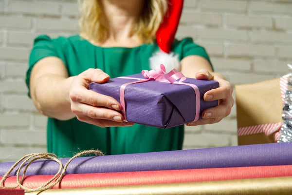 女性的手拿着一个用包装纸包裹的小礼品盒。送给和接受所爱的人送给他们的圣诞礼物，情人节礼物，生日礼物. — 图库照片