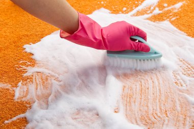 Halıdaki lekeyi sert fırçayla temizleyen kadın. Turuncu halı temizliği. halı temizleme hizmeti konsepti