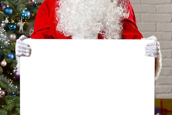 Santa Claus sosteniendo pizarra blanca con espacio para copias. Santa Claus se apoya en una pizarra blanca con espacio para ofertas navideñas. — Foto de Stock