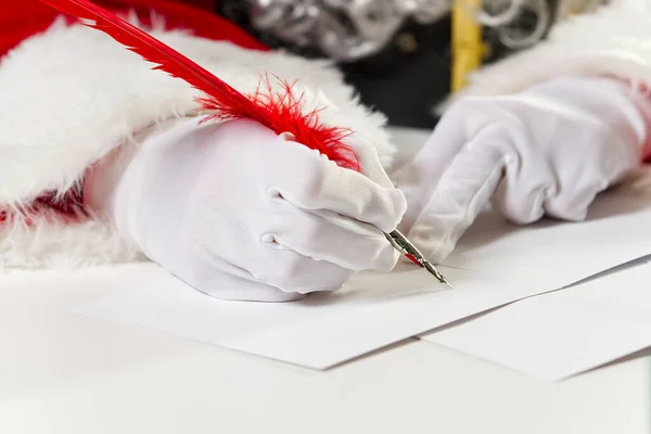 Costumed hands of Santa Claus writing a Christmas letter or greeting on a postcard. close up — Stock Photo, Image