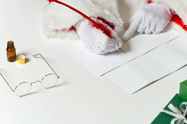 Manos disfrazadas de Santa Claus escribiendo una carta de Navidad o un saludo en una postal. de cerca — Foto de Stock