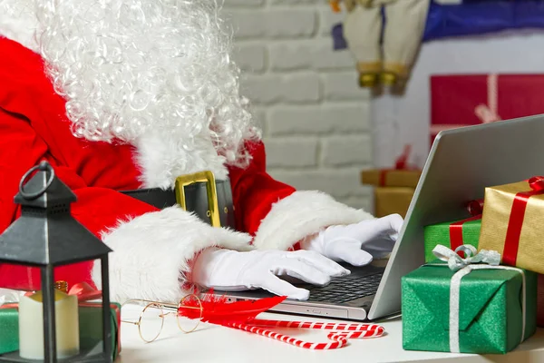 Papá Noel sentado detrás del portátil. Santa Claus en un encierro sentado detrás de un ordenador portátil conduce a la comunicación en línea. — Foto de Stock