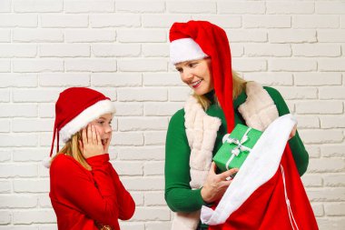 Anne, Noel Baba çantasından kızına hediye paketi almış. Noel Baba ve bir çanta dolusu Noel hediyesi.