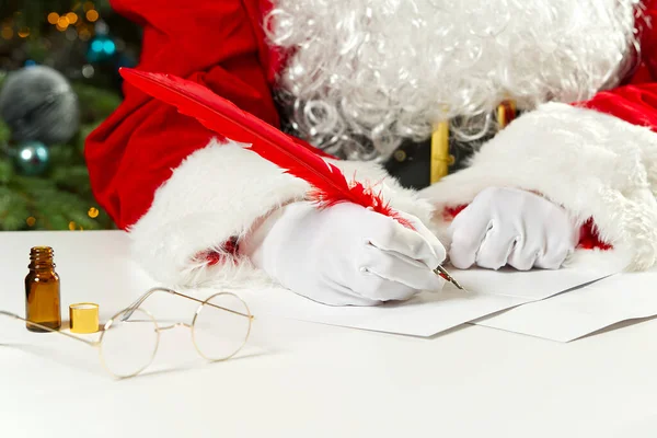 Kostiumy Świętego Mikołaja piszące świąteczny list lub pozdrowienia na pocztówce. zbliżenie — Zdjęcie stockowe