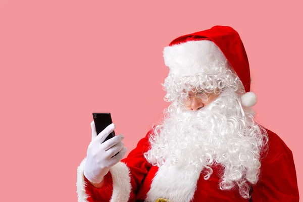 Weihnachtsmann mit Handy isoliert auf rosa Hintergrund — Stockfoto