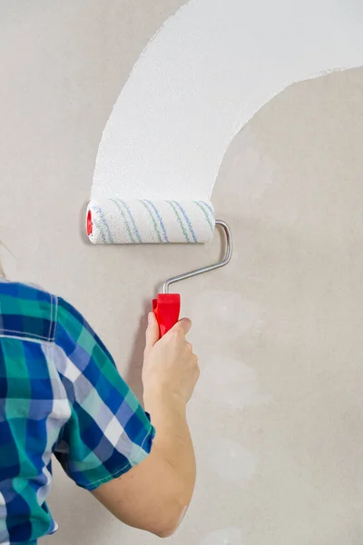 Karton duvarı beyaza boyayan bir kadın. Ev onarımı, silindirli alçıpan boyası. — Stok fotoğraf