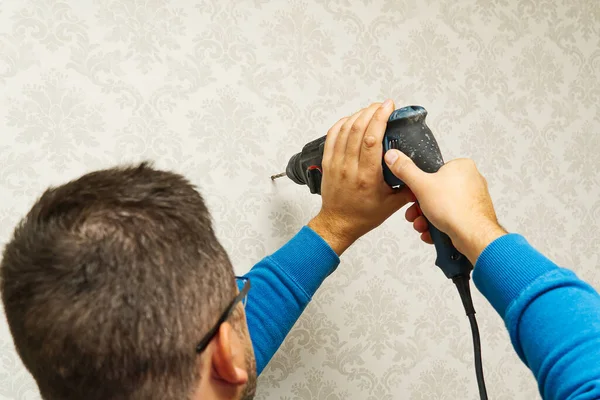 home worker use Electric power drill to drill the concrete wall with wallpapers