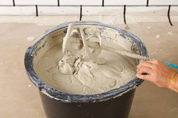 the master mixes the plaster in a bucket. Flat house renovation, master mixed the mortar in a plastic bucket with mixer