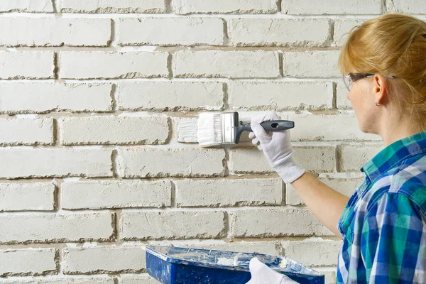 Ремонт стены DIY, Женщина рисует стену из белого брика кистью — стоковое фото
