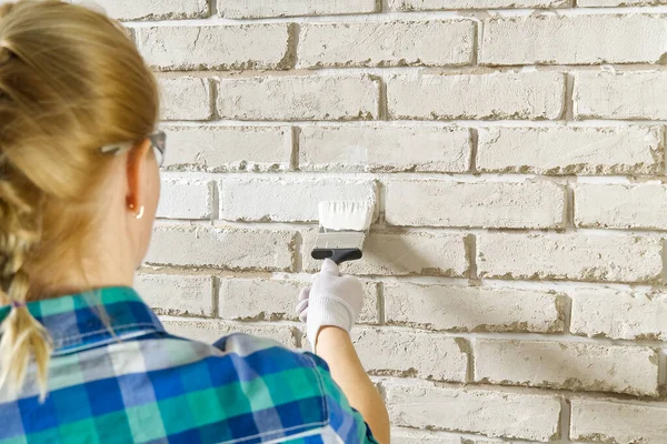 DIY duvar onarımı, bir kadın boya fırçası ile beyaz tuğla bir duvar boyama — Stok fotoğraf