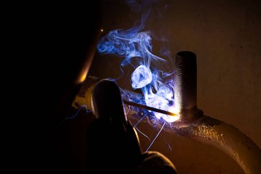 Eski elektrikli metal borularla ısıtma için profesyonel kaynakçı. Eski ısıtma sistemi yenileme kavramı