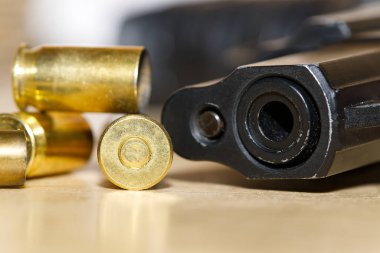Atış poligonunda ya da suç mahallinde, tahta bir masanın üzerine yakın plan mermi kovanları ve namlu. suç kavramı