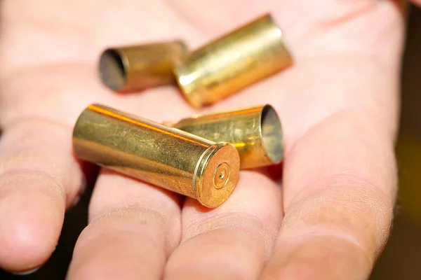 Close-up de caixas de cartucho de bronze em uma mão em um alcance de tiroteio ou em uma cena de crime. conceito de crime — Fotografia de Stock