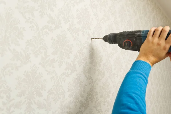 home worker use Electric power drill to drill the concrete wall with wallpapers