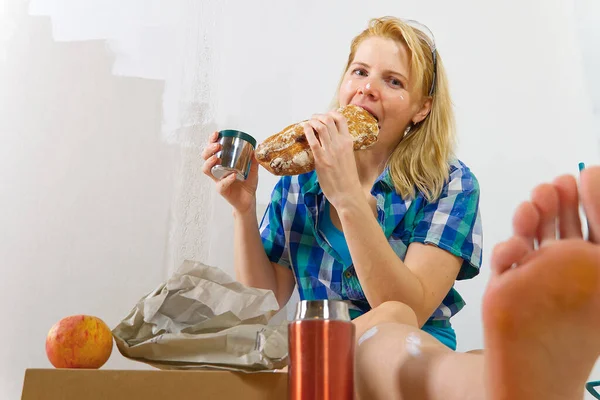 Vrouw schilder lunchen in de faciliteit, huis reparateur luncht na het werken in huis, — Stockfoto