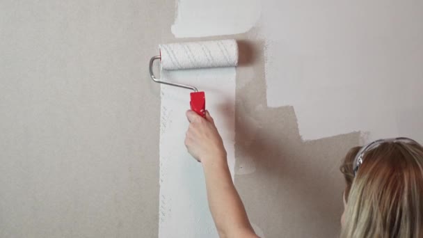 Mulher com rolo de pintura e pintura branca pintura drywall — Vídeo de Stock