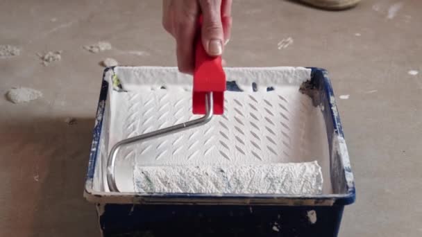Der Arm der Arbeiter taucht die Walze in weiße Farbe, um die Wand zu streichen — Stockvideo