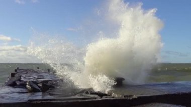 Bahar güneşli bir günde Baltık Denizi 'nde, Tallinn' de, parlak mavi gökyüzünün arka planına karşı iskelede büyük dalgalar salıyor.