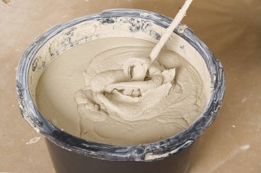 Usta alçıyı kovada karıştırır. Düz ev tadilatı, usta havanı plastik kovayla karıştırıcı ile karıştırmış.