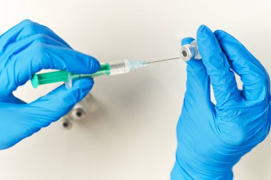 Doktor, şırıngayı küçük bir şişeye aşı ya da ilaç enjekte ederek virüs ya da grip aşıladı..