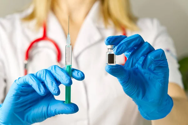 Arts handen injecteert een injectienaald in een flesje met een vaccin of medicijn wijst virus of griep toe. — Stockfoto