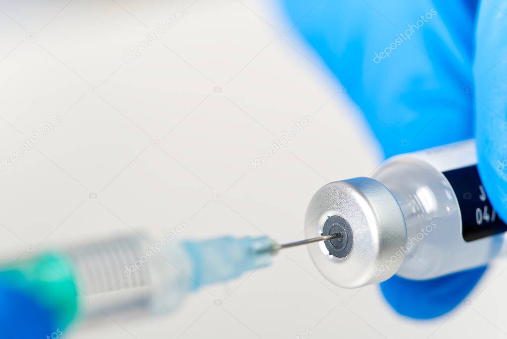 doctor hands injecting a syringe needle into a small bottle with a vaccine or drug assign virus or flu.