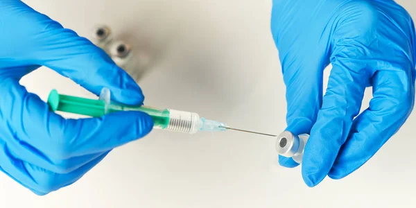 Ręce lekarza wstrzyknięcie igły strzykawki do małej butelki ze szczepionką lub lekiem przypisać wirusa lub grypy. — Zdjęcie stockowe