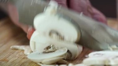 Kadınların elleri, şampiyonları karanlık mutfak masasında bıçakla kesiyor. Mantar yemeği konsepti.