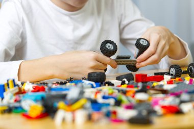 Genç çocuk evde plastik inşaat oyuncaklarıyla oynuyor..
