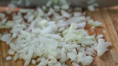 Şef tahtadan soğanları kesiyor.