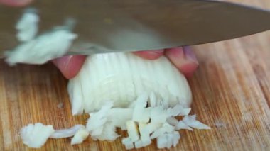 Şef tahtadan soğanları kesiyor.