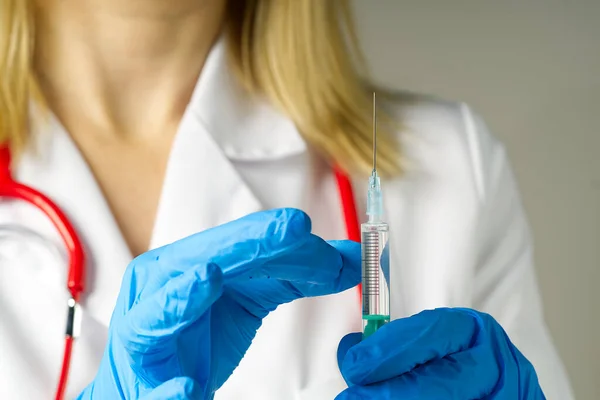 Arts handen injecteert een injectienaald in een flesje met een vaccin of medicijn wijst virus of griep toe. — Stockfoto