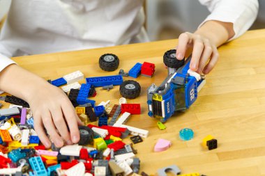 Genç çocuk evde plastik inşaat oyuncaklarıyla oynuyor..