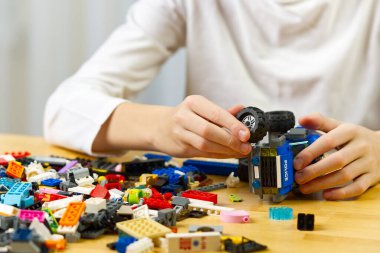 Genç çocuk evde plastik inşaat oyuncaklarıyla oynuyor..