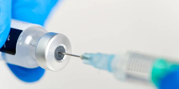 doctor hands injecting a syringe needle into a small bottle with a vaccine or drug assign virus or flu. macro syringe and vaccine, medical health concept. COVID-19