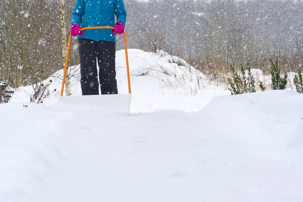 Donna che pulisce la neve con la pala durante la giornata invernale. Donna spalare passerella di neve di fronte alla casa — Foto Stock