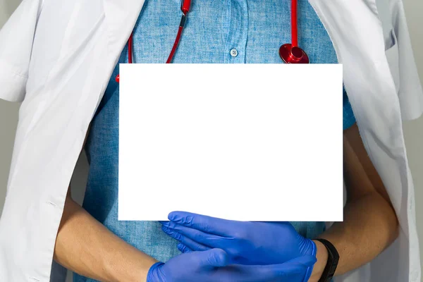 Médico segurando em mãos banner branco em branco, mockup — Fotografia de Stock