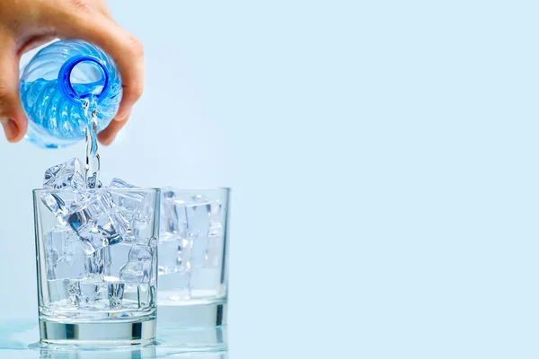 Verser de l'eau potable propre de bouteille en plastique bleu dans du verre sur fond bleu — Photo